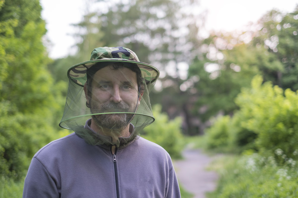 Un homme porte un chapeau anti-insecte avec filet. 