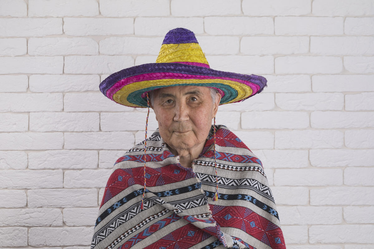Photo d’un Mexicain. Il est vêtu d’un manteau nommé poncho et d’un chapeau à large rebord nommé sombréro. 