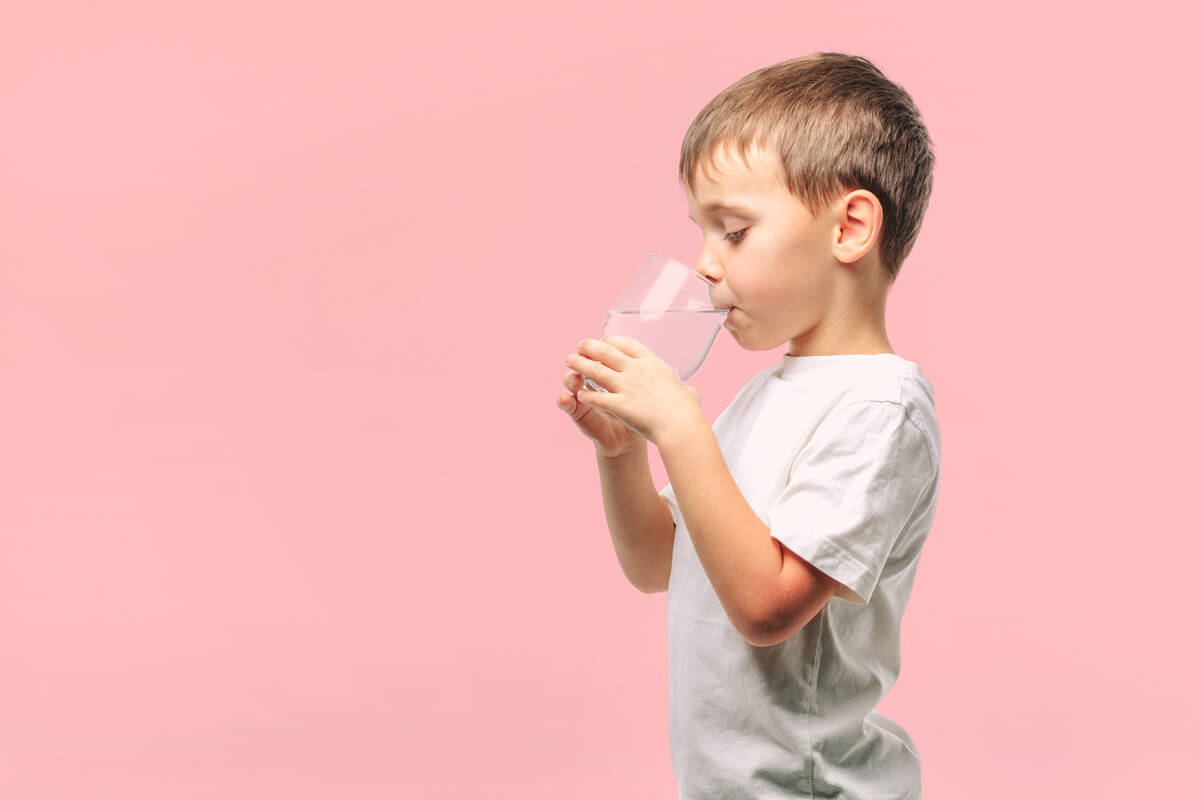 Un enfant qui boit un verre d'eau. 