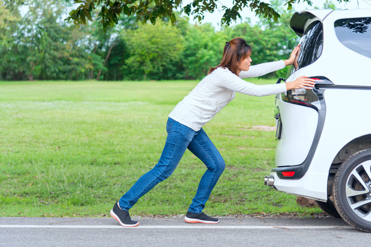 Une femme poussant une voiture. 